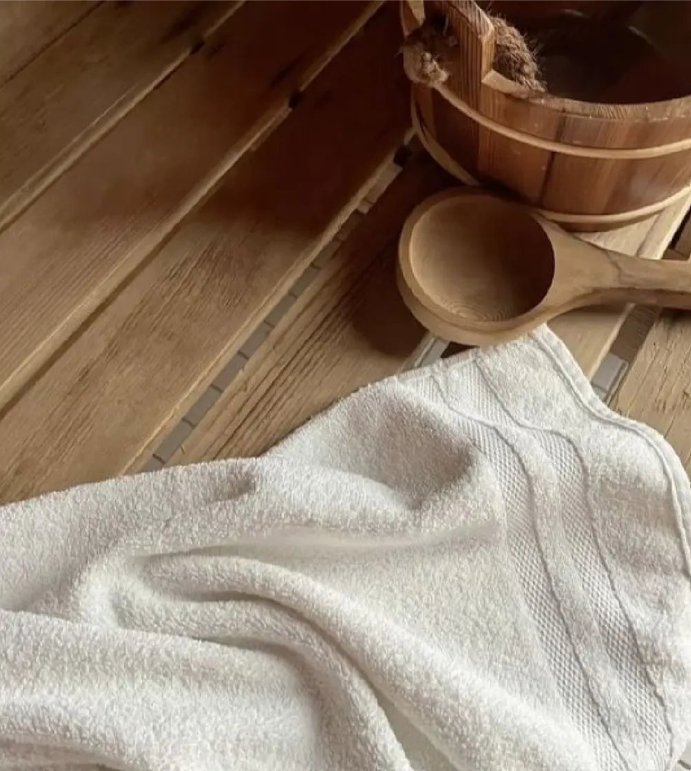 Detalle de sauna con tina de madera y toalla blanca.