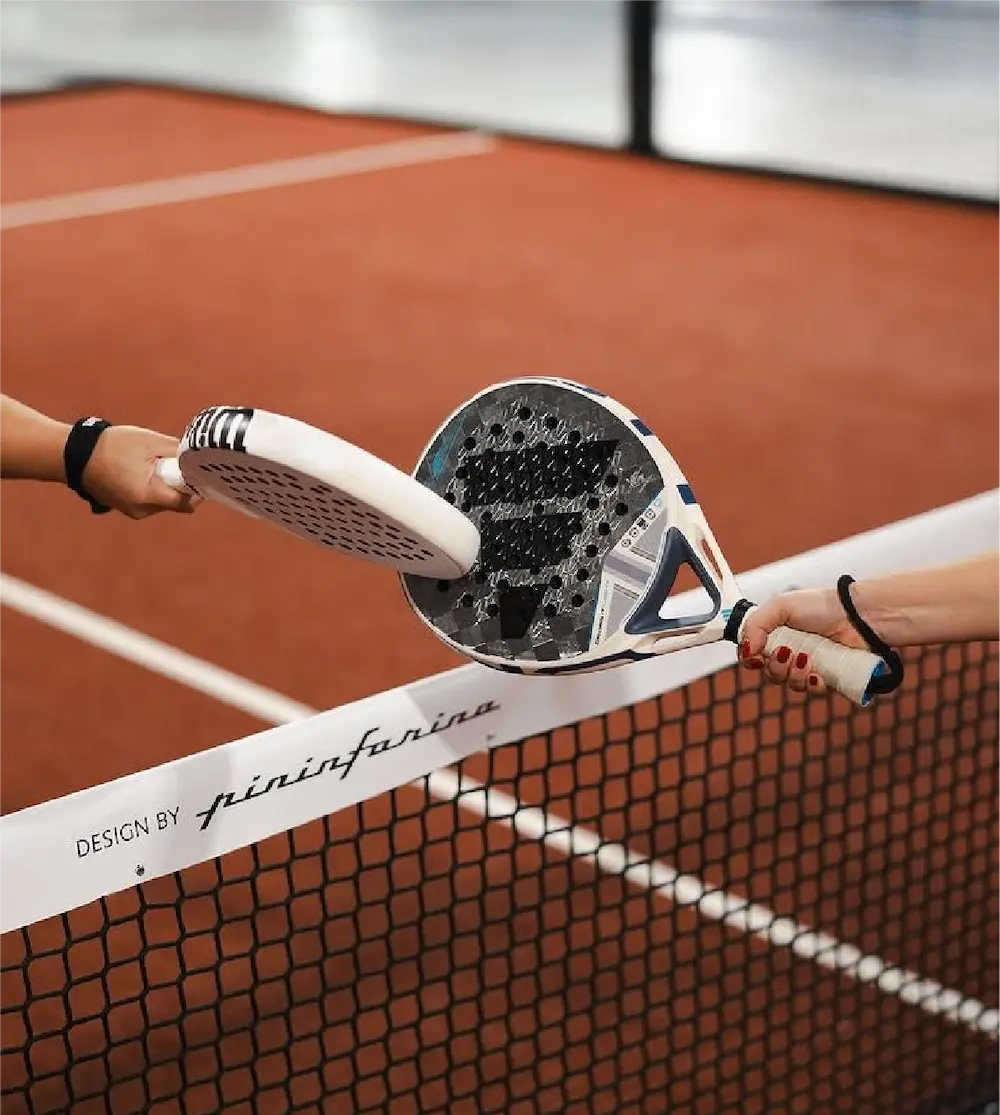 Personas jugando padel sobre una cancha terracota.